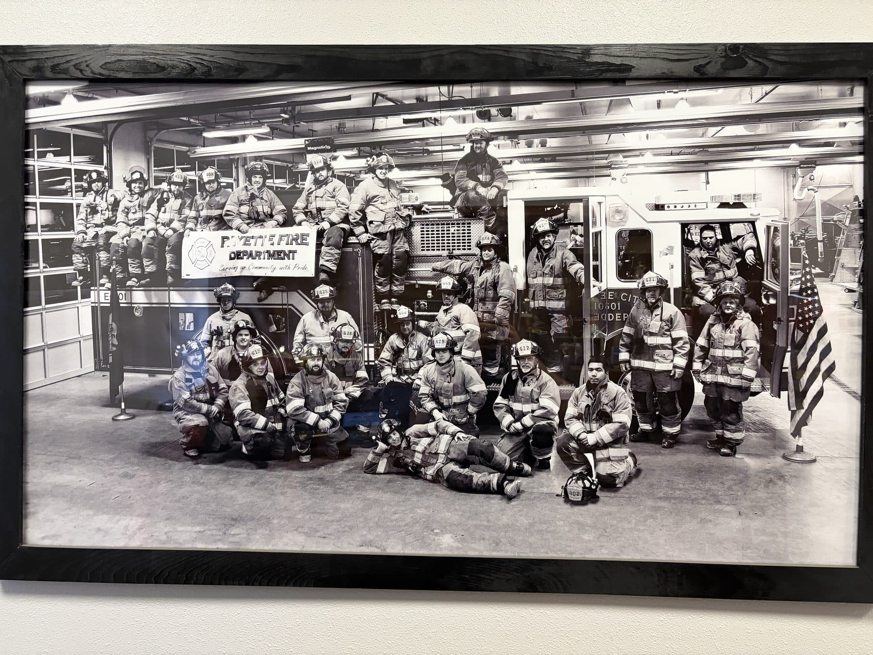 The Payette Fire Department in full turnout gear posed around an engine in the apparatus bay, with a department banner reading 'Serving our Community with Pride'