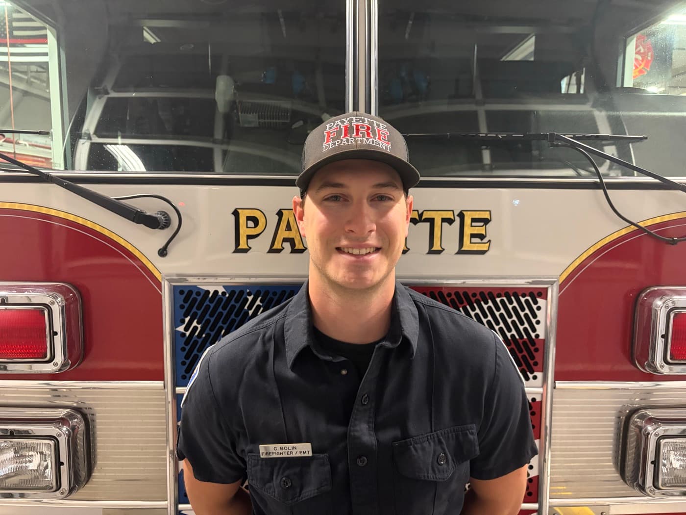 Firefighter and EMT Christopher Bolin in uniform, standing in front of a Payette fire engine.