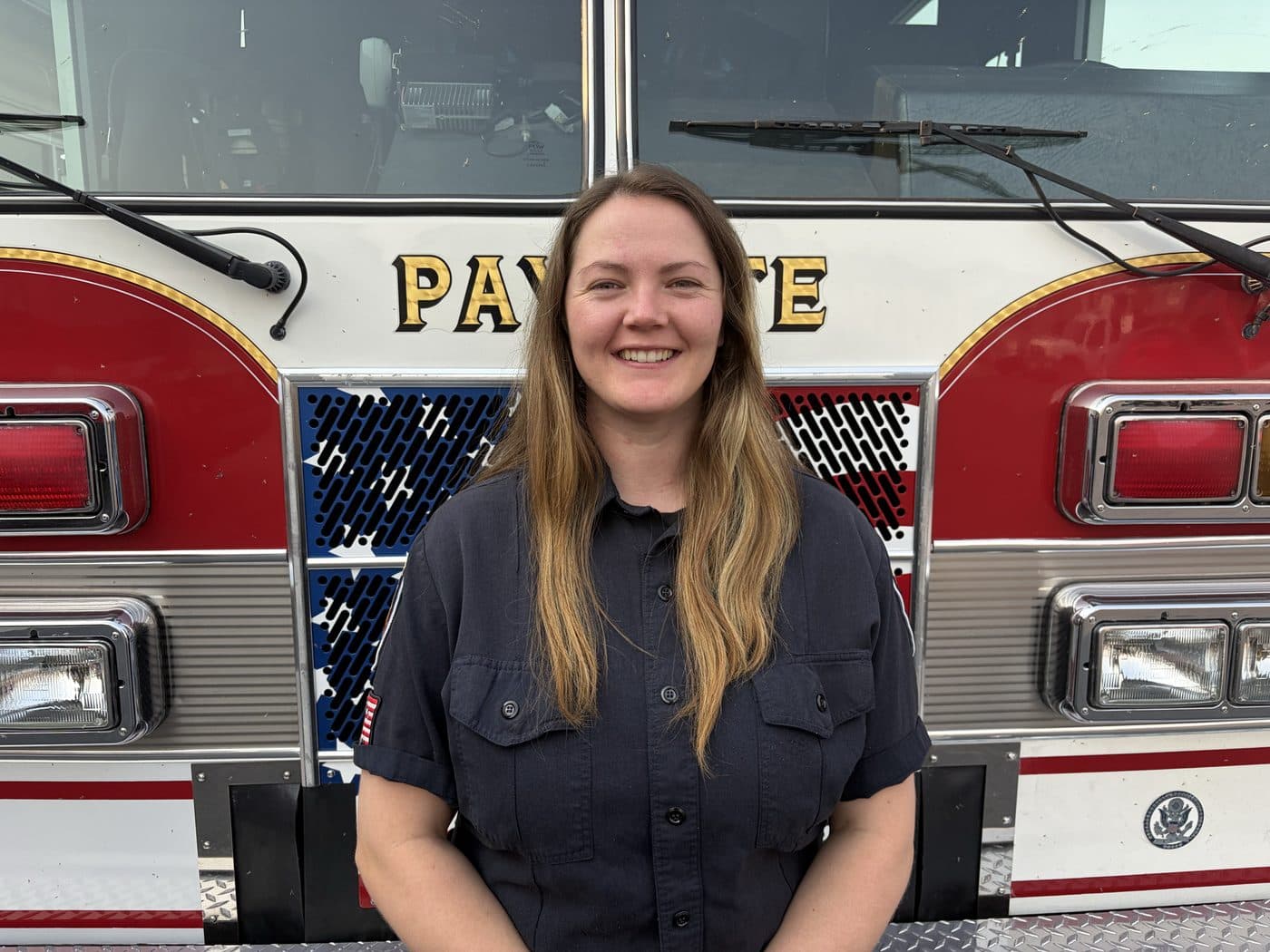 Firefighter and EMT Kylee Decker in uniform, standing in front of a Payette fire engine.