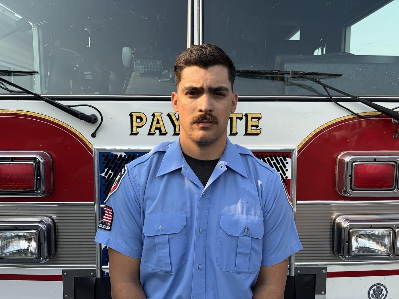 Volunteer Firefighter and EMT Renn Hambright in uniform, standing in front of a Payette fire engine.