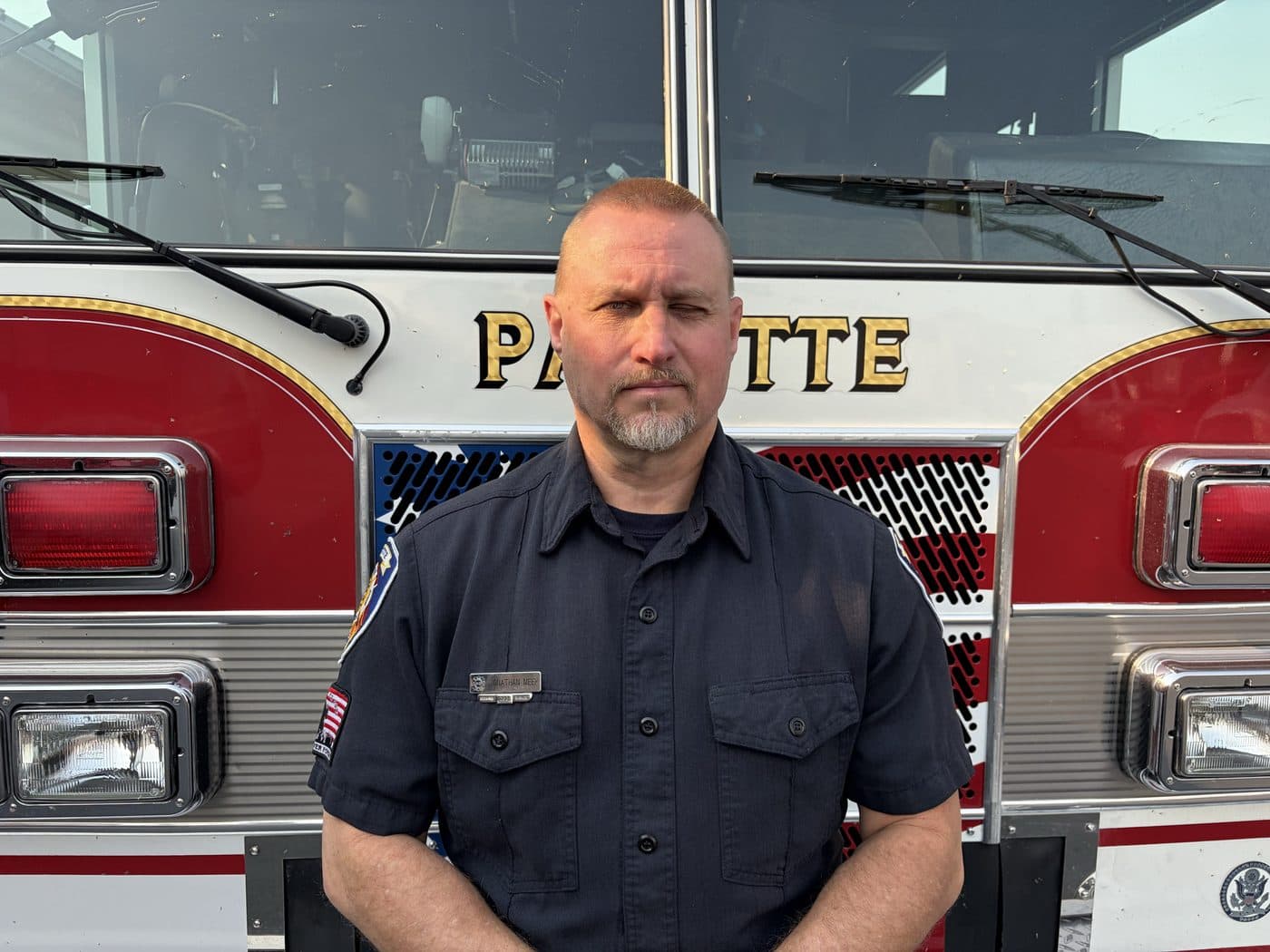 Engineer and EMT Jon Meek in uniform, standing in front of a Payette fire engine.
