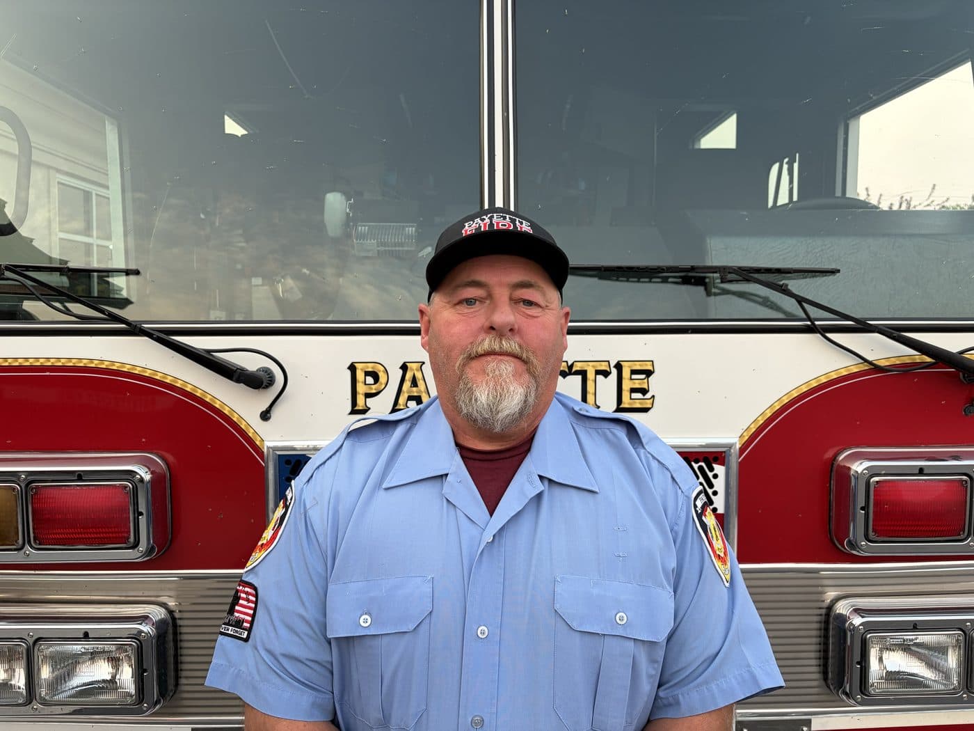 Volunteer Firefighter Kevin Petty in uniform, standing in front of a Payette fire engine.