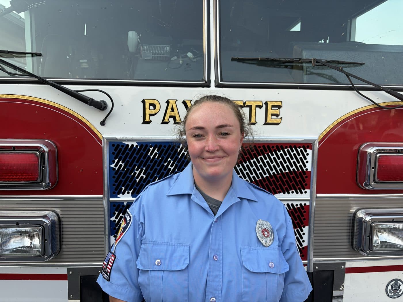 Volunteer Firefighter and EMT Erin Winsor in uniform, standing in front of a Payette fire engine.